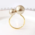 Close-up of golden double pearl napkin ring with champagne pearls on a white plate - Champagne