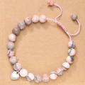 Close-up of pink zebra jasper beads and silver heart charm on an adjustable bracelet - Braided Pink Zebra Heart Style