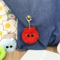 Detailed shot of a cute red plush keychain ball with sunglasses attached to a denim bag - Red