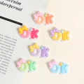 Macro view of colorful resin 'OK' charms with bow and heart for DIY accessories - Kill You Black