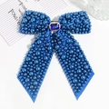 Detail view of navy blue ribbon bow hair clip with pearls and a rectangular blue gemstone - Blue