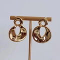 Detail view of 18K gold plated earrings with abstract organic fluid shape on a gold stand - Round Disk (D314) / Gold
