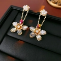 Macro shot of floral drop earrings with zircon, pearls and gold finish on black leather - Multicolor-Colorful Rhinestone (HE23405)