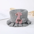 Detail eines grauen Baby-Strickschals mit rosa Giraffe und Handmade-Etikett - Grau
