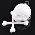 White skull and crossbones silicone tea infuser with metal chain on black background - Skull
