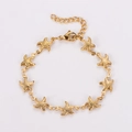 Detalle macro de la pulsera de estrella de mar dorada con dijes y cierre de mosquetón - Dorado