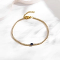 Macro detail of gold-plated chain bracelet with blue zircon center and white gemstones - Round Dark Blue Zirconia