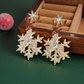 Details von Weihnachts-Rentier-Ohrringen mit Schneeflocken und Strass auf einer Holzbox - Gold