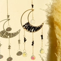 Detail of moon suncatcher with black crystals and rainbow light reflections on the wall - Obsidian Moon Wind Chime