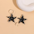 Macro detail of 3D starfish charms with white polka dots on black glossy glass surface - Black