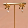 Elegant gold flower earrings with natural freshwater pearl drops on jewelry stand - Lotus Flower Studs