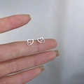 925 silver stud earrings with interlocking double hearts design on fingers - Heart-to-Heart / Silver