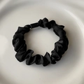 Detalle de coletero de satén negro con hebilla rectangular sobre plato blanco - Negro