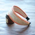 Detail of beige raffia woven headband with orange stitching on a rustic wooden background - Beige with Orange Stitching