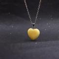Macro shot of a yellow heart-shaped natural stone pendant on a silver link chain - Yellow Jade with Chain