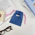 Detailweergave van een blauw geruit opbergzakje met een roze trekkoord en een wit label - Blauw Rooster