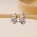 Detail of silver floral earrings with cubic zirconia clusters hanging on a wooden branch - Top and Bottom Floral Cluster Zirconia Earrings-Silver