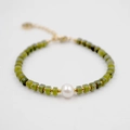 Bracelet en perles de jaspe vert avec perle blanche centrale et accents dorés sur fond blanc - Style Pierre Verte