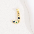 Detail of a gold letter J pendant with colorful zircon stones on a white background - Letter J