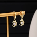 Detail der goldenen Mond-Huggie-Ohrringe mit glitzerndem Zirkonia auf Schmuckständer - Mond