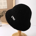 Detail of black faux shearling bucket hat with soft plush texture on a wooden stand - Black