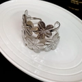 Macro shot of silver floral cuff bracelet with brushed metal texture on white ceramic tray - 4# Armlet - Double Flower Silver
