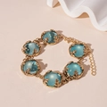 Close-up of vintage golden bracelet with blue resin stones and intricate leaf claws - Blue Resin Bracelet