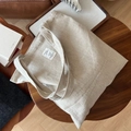 Close-up of oatmeal beige canvas tote bag with natural linen texture and a white label - Solid Beige Style