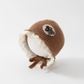Detailed close-up of baby knit bonnet with white lace trim and floral bow decoration - 48cm (6-20 Months) / Brown