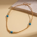 Detail of 18K gold-plated beaded necklace with blue stones on a stone surface - Necklace - Gold (Gold Plated)