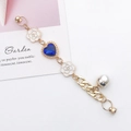 Detail of golden chain with heart-shaped blue gem and white camellia flower charms - Sapphire Blue