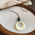 Détail macro du pendentif géométrique en acrylique avec perles bohèmes sur bois - Cordon Marron Anneau Rond Beige