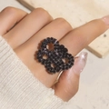 Close-up of a large black crystal interlaced heart ring worn with a knit sweater - Adjustable Open / Black Interlocking Heart Style (6025BK)