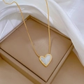 Détail macro du collier en acier titane doré avec pendentif cœur en nacre blanche élégant - Doré