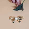 Elegant golden metal bow hair clip featuring a large white pearl center on pink background - Gold
