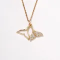 Detail view of gold whale tail pendant with sparkling pavé cubic zirconia accents - Gold Double Fish Tail