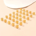 Detailed view of 25 golden hollow geometric hair rings for dreadlocks on pink surface - 30Pcs Q936 Hollow Flower Braid Rings