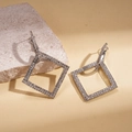Detailopname van zilveren vierkante oorringen met kristallen op een stenen ondergrond - Zilver (Zilveren pin)