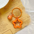 Detail shot of an orange star keychain with small bell on vintage newspaper background - Orange