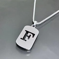 Vue macro du collier en titane argenté avec un pendentif ajouré de la lettre F - Lettre F / Argent