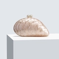Detail einer schalenförmigen Acryl-Abendtasche mit Perlenverschlüssen auf weißem Podest - Champagner