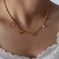 Golden twist chain necklace with five colorful heart-shaped zirconia pendants worn by model - Gold/Multicolor