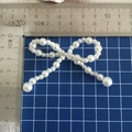 Detalle de lazo de perlas blancas sobre tapete de corte con ancho de 5,5 cm - Perla alterna pequeña / 5cm x 5cm