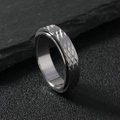 Macro shot of silver 6mm rotatable ring with diamond pattern on black stone surface - US 7 / Steel