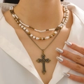 Detail of layered vintage cross necklace with pearls and bronze chains worn on neck - Layered Bronze Metal Bead Cross Style