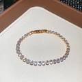 Detalle de pulsera tenis de oro de 18k con cristales redondos sobre fondo de cuero - Oro-Circón Redondo Blanco