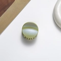 Detailed close-up of a mini green pearlescent shark hair claw clip for kids hair styling - Green