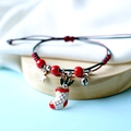 Macro shot of hand-woven Christmas bracelet with Santa sock charm and silver bells - Rhinestone Stocking