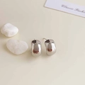 Macro shot of silver-plated chunky hoop earrings on decorative white stones - Rhodium Plated Silver C-shaped Bean Studs