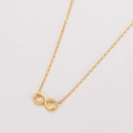 Vue macro du pendentif infini doré avec cristaux pavés sur une fine chaîne croisée - Collier Or